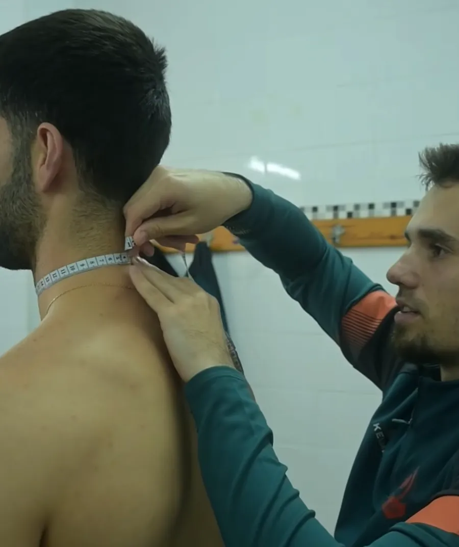 Gonzalo midiendo el perímetro de cuello a un jugador en el vestuario